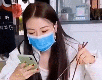美女一边玩手机一边吃面条，没想到口罩忘记摘了