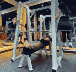 猛男在健身房卧推两位美女